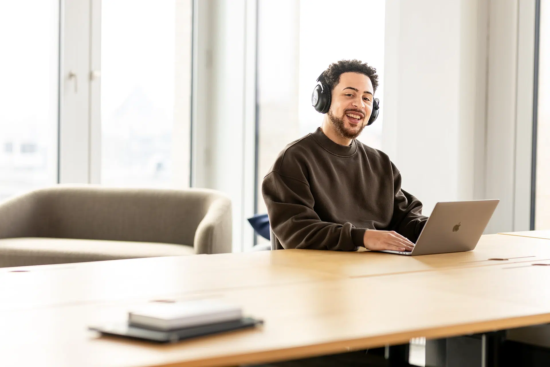 Lachender Mann sitzt am Laptop