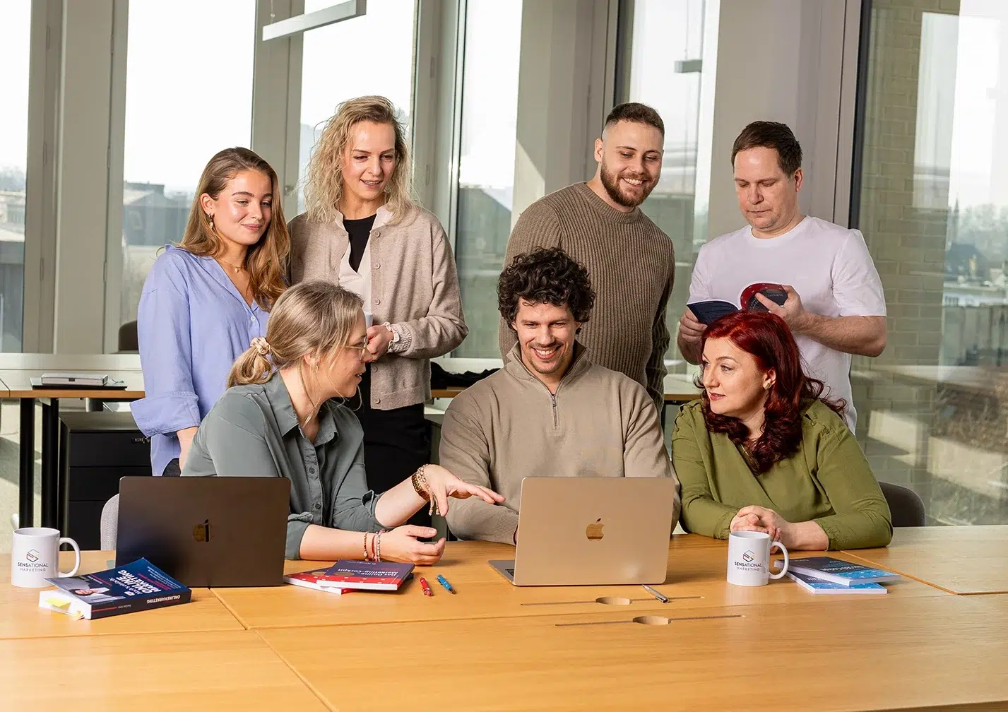 Ein Team in einem großen Büro bespricht etwas an einem langen Tisch