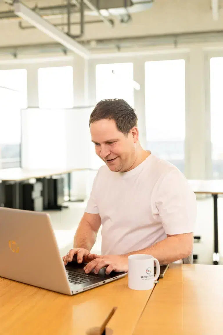 Ein lächelnder Mann sitzt am Laptop