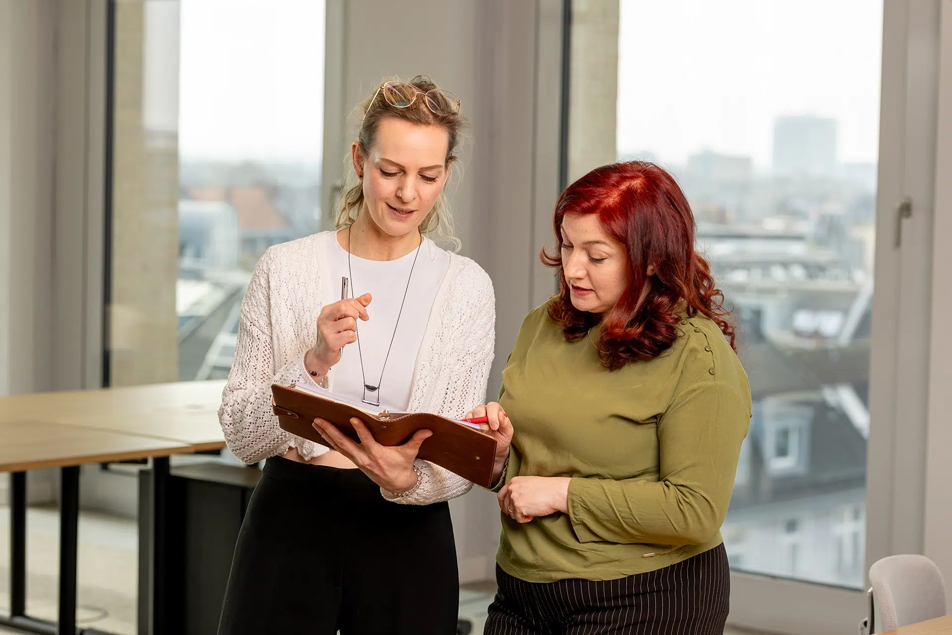 Zwei Frauen besprechen etwas über einem aufgeklappten Ordner